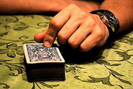 A hand placing a deck of cards beside chips on a patterned cloth