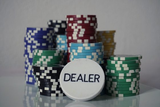A white dealer button in front of stacked poker chips