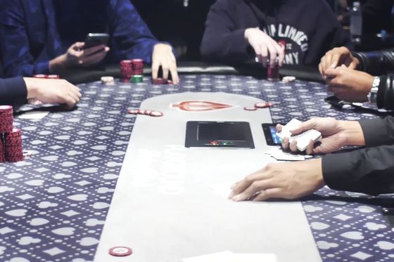 Overhead view of players' hands, cards and chips on a poker table